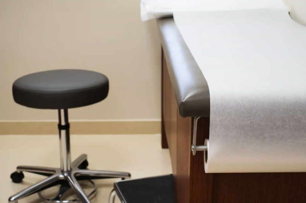 Doctors Office Paper Covered Examination Table And Stool
